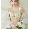 A model modeling the soft Champagne colored lace bra suit with green floral vine embroidery accents,