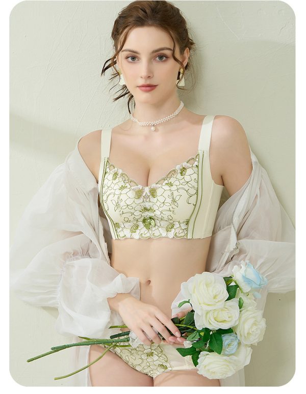 A model modeling the soft Champagne colored lace bra suit with green floral vine embroidery accents,