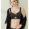 A model showcasing the elegant Mysterious Black lace push-up correction bra suit featuring gold contrast floral embroidery, fixed double shoulder straps, and matching panties,
